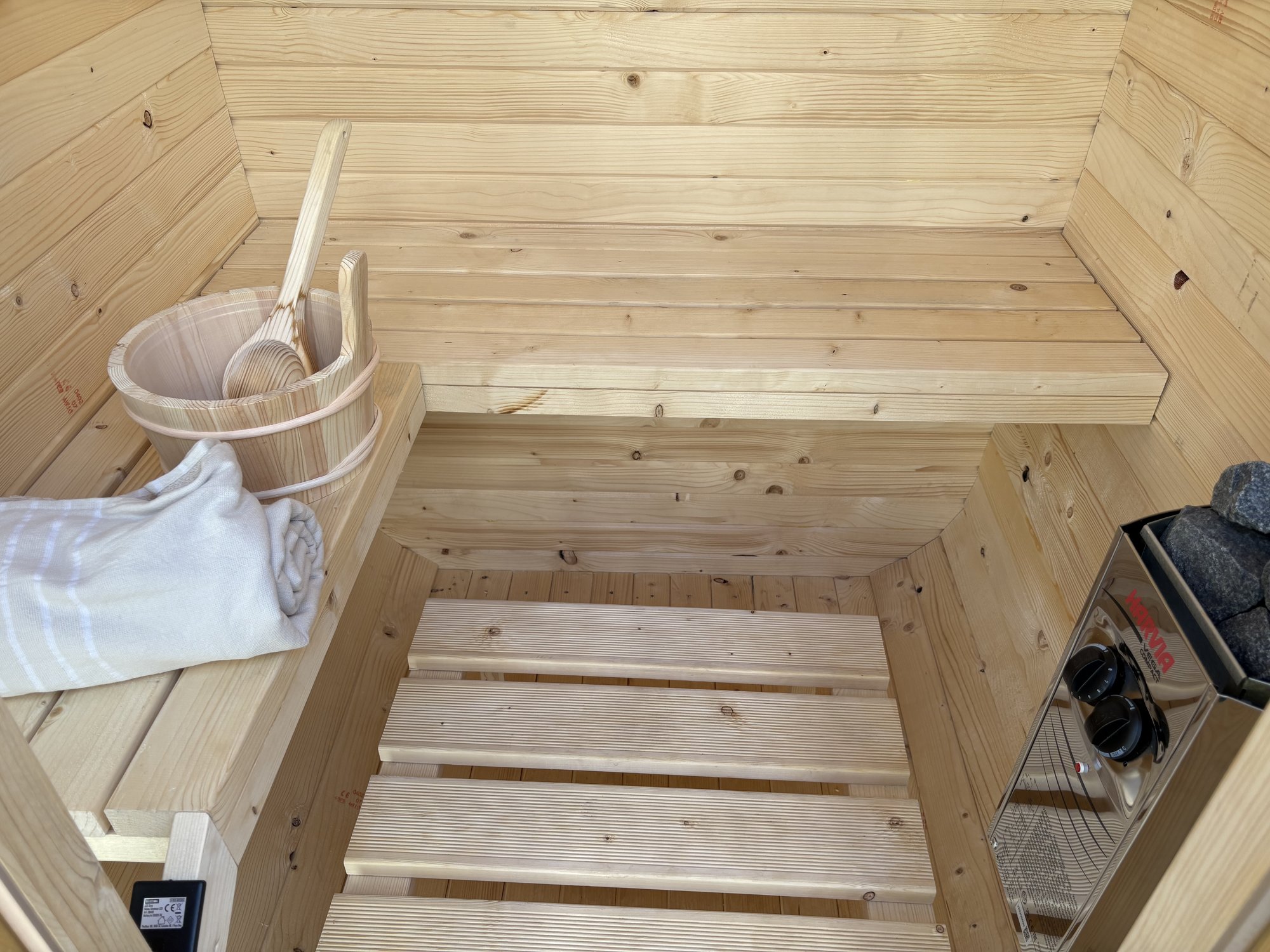 Interieur van de Nordic Cube met handdoeken en Harvia kachel